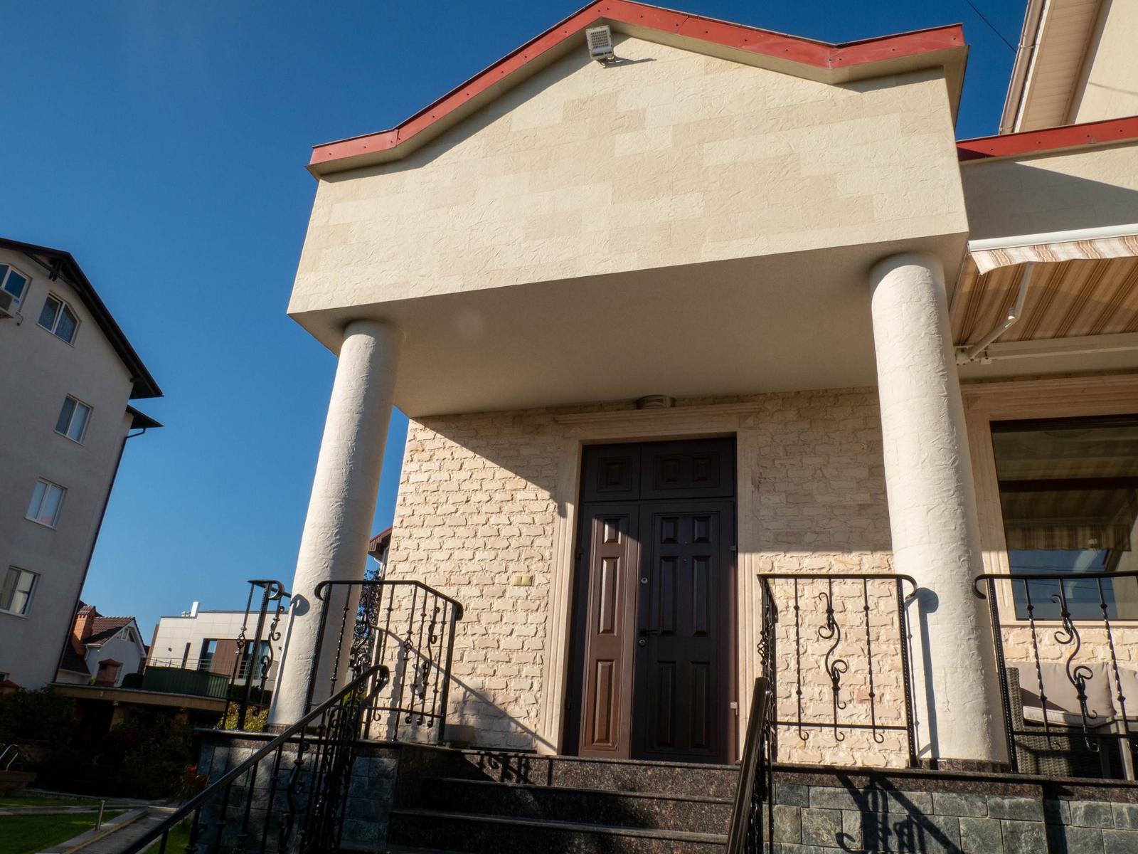 Volum în consolă sprijinit pe două coloane rotunde placate cu piatră flexibilă